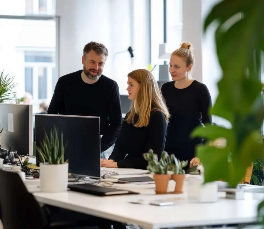 Madcraft Team discussing digital transformation around a computer in a modern office